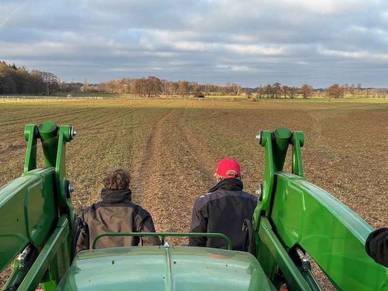 Rückansicht von zwei Menschen, die in der Schaufel eines Traktors sitzen