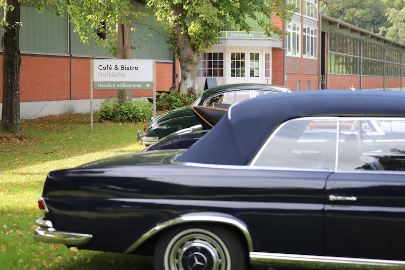 Oldtimer parken aus einer Ausfahrt auf dem Hofrondell vor der Hofküche